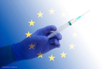 A gloved hand holding a syringe, superimposed over the European Union flag. Image credit: ©Savvapanf Photo – stock.adobe.com