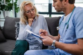 A doctor reviews paperwork with a woman. Image credit: ©Drazen – stock.adobe.com