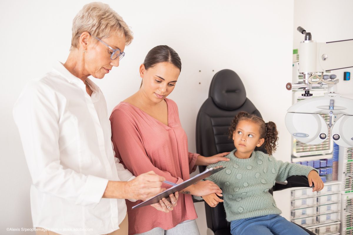 Following her eye exam, a young girl waits for her mother and her doctor to finish a discussion. Image credit: ©Alexis S/peopleimages.com – stock.adobe.com