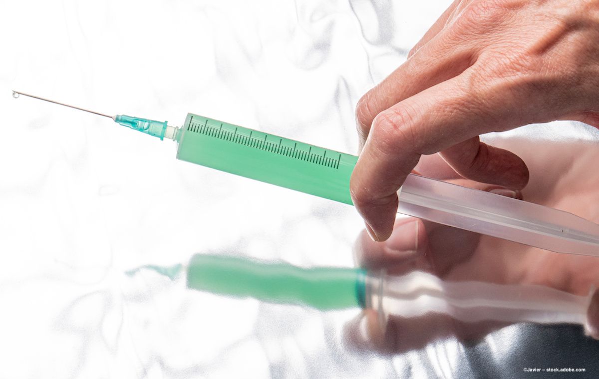 A syringe full of green liquid is held above a mirror. Image credit: ©Javier – stock.adobe.com