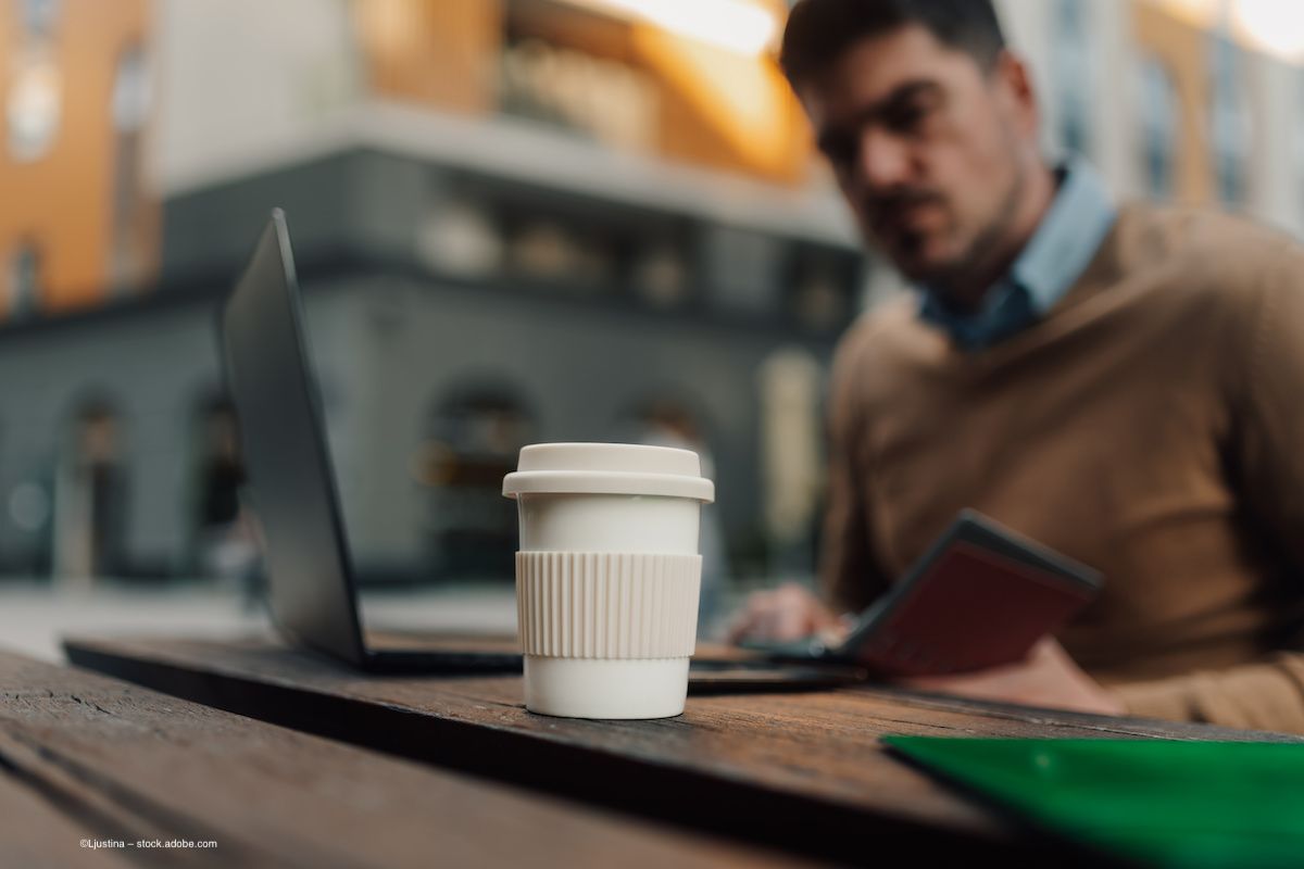 A person sits at their laptop with a cup of coffee visible in the foreground. Concept image for instant coffee, AMD, age related macular degeneration, ocular health and instant coffee investigation. Image credit: ©Ljustina – stock.adobe.com