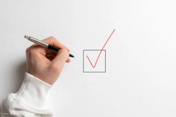 A hand writes a red check mark into a box on a white background. Image credit: ©Mihail – stock.adobe.com