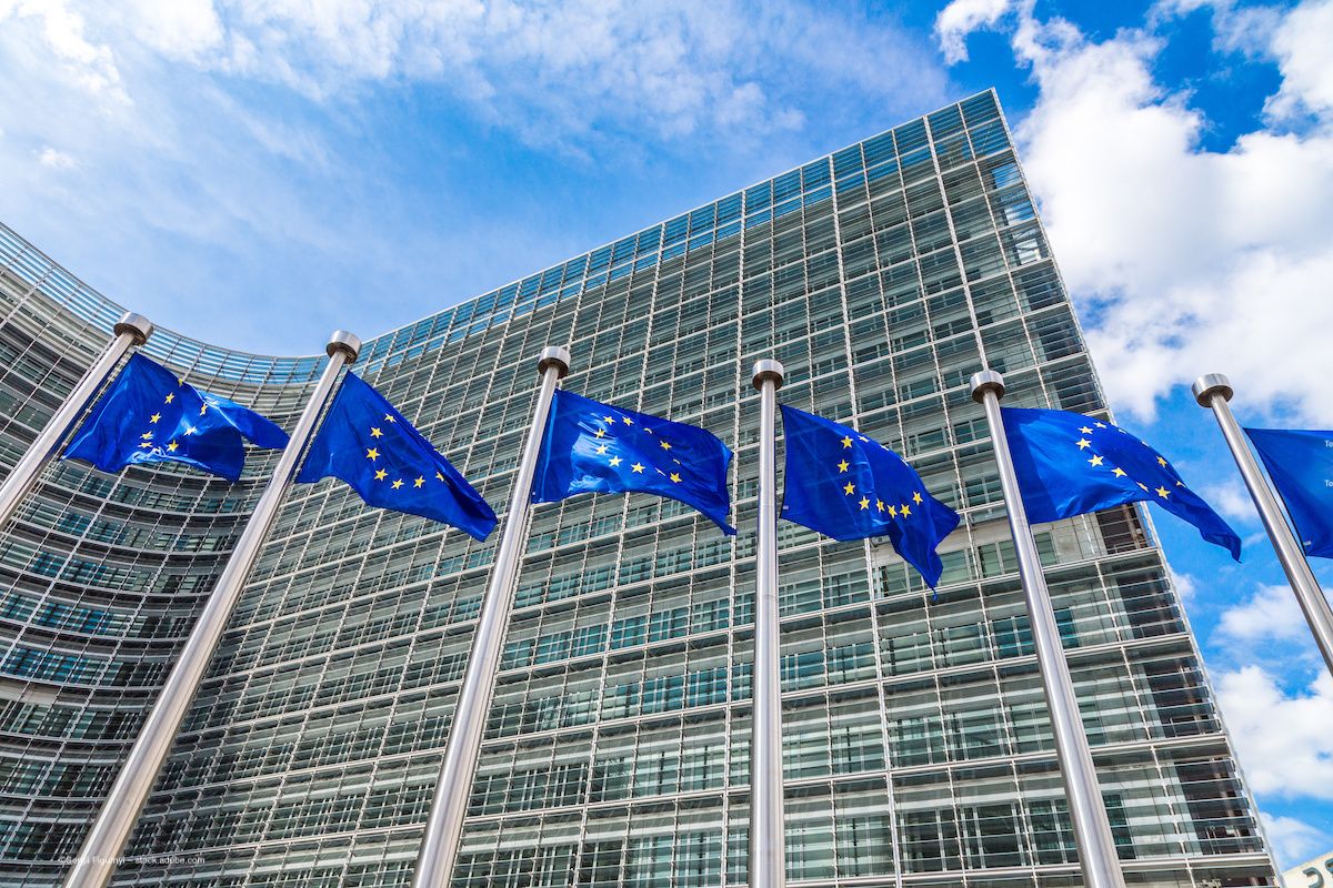 EU flags wave in the wind outside a building. Image credit: ©Sergii Figurnyi – stock.adobe.com