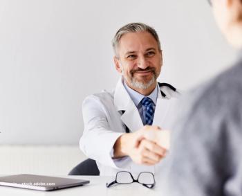 A doctor in a white coat shakes hands with someone off-screen. Image credit: ©bnenin – stock.adobe.com