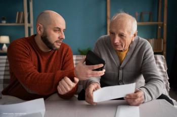An elderly man and his caregiver discuss their budget and financial well-being. Concept image for caretaker, caregiver, aging, age-related macular degeneration. Image credit: ©Andrii Lysenko – stock.adobe.com