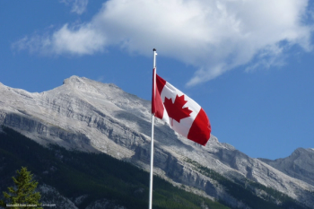 A Canadian flag in front of a mountain range. Concept image for Alcon Clareon Panoptix Pro intraocular lens IOL launch and approval in Canada. Image credit: ©toptop54 from pixabay - Canva.com