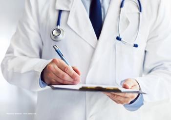 A doctor in a white coat holds a clipboard. Image credit: ©Rostislav Sedlacek – stock.adobe.com