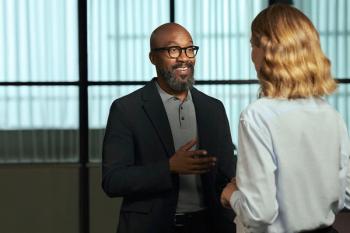 A man wearing Nuance Audio hearing aid glasses speaks to a friend. Image courtesy of EssilorLuxottica