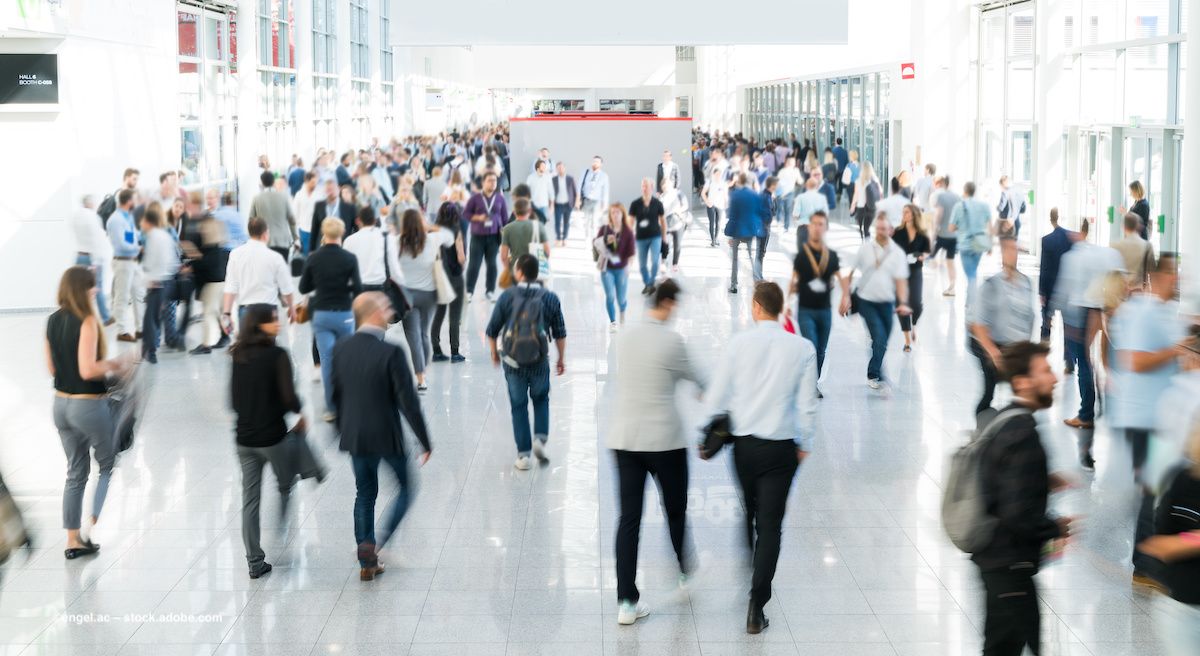 A crowd of people move about a conference floor. Image credit: ©engel.ac – stock.adobe.com