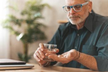 A man wearing glasses prepares to take medication in pill form. Image credit: ©Andrii Zastrozhnov – stock.adobe.com