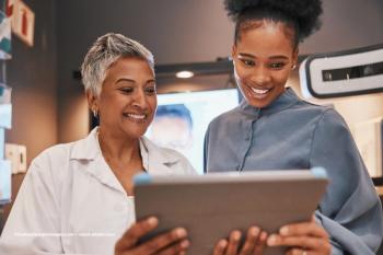A physician and patient look at a chart together. They're both smiling. Image credit: ©Coetzee/peopleimages.com – stock.adobe.com