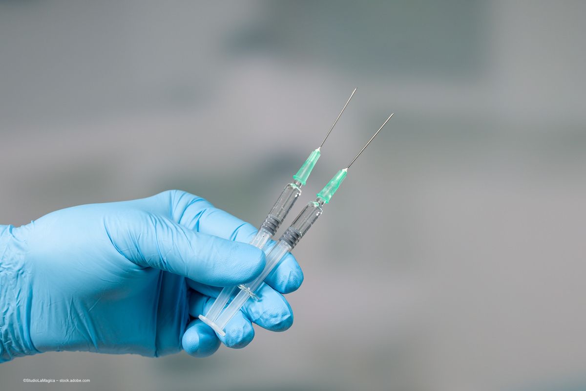 A gloved hand holds two syringes full of fluid. Image credit: ©StudioLaMagica – stock.adobe.com