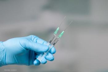A gloved hand holds two syringes full of fluid. Image credit: ©StudioLaMagica – stock.adobe.com
