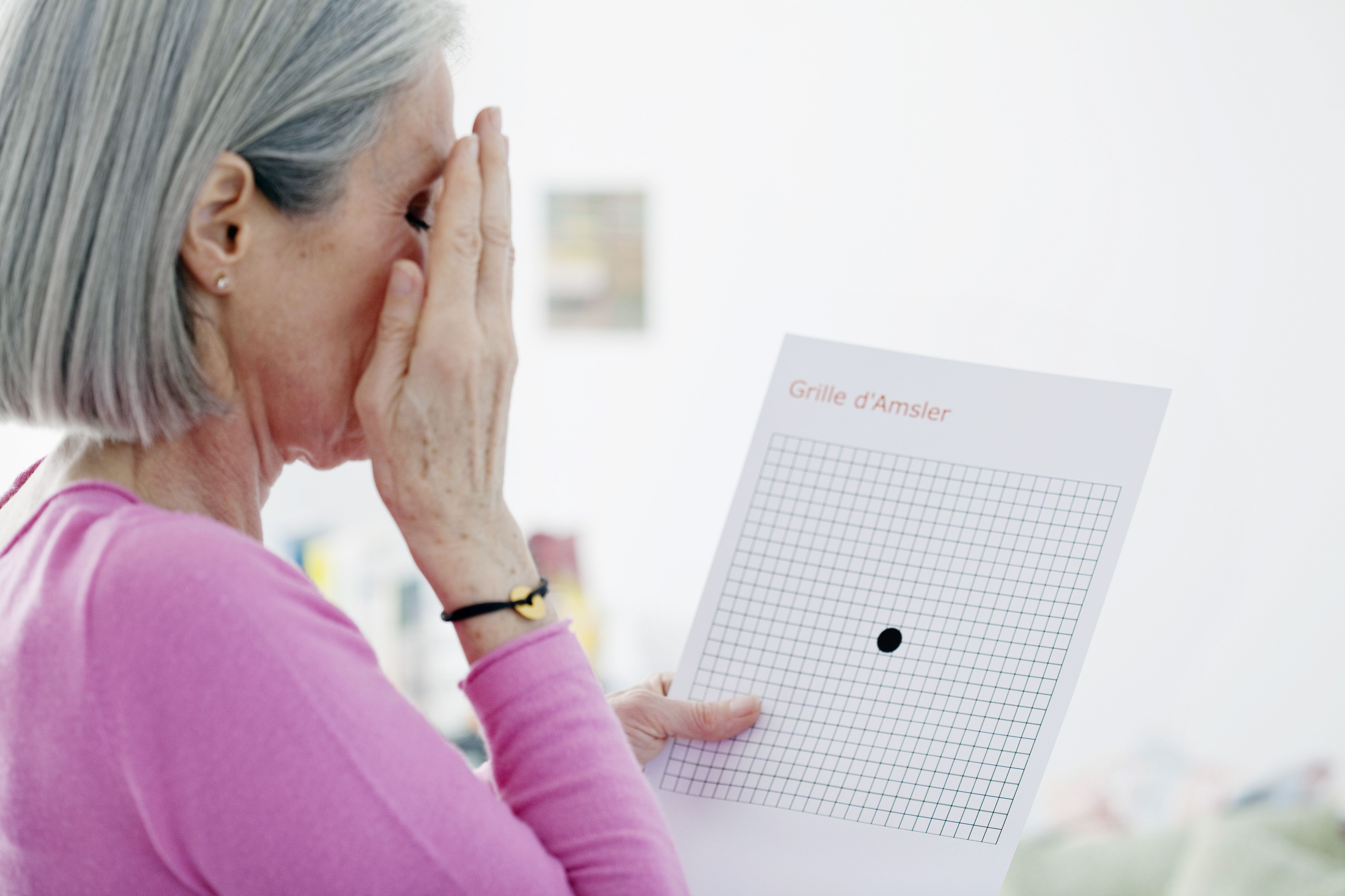 Woman looking at Amsler grid, used to screen an ARMD, Age-related macular degeneration