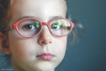 A child looks at the camera. She has on red glasses. Image credit: ©Annashou – stock.adobe.com