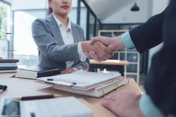 Business partners shaking hands at table Image credit: AdobeStock/Kritdanai