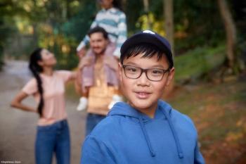 Boy wearing DOT lenses with family in background Image credit: SightGlassVision