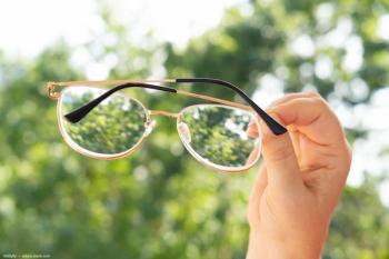 Hand holding pair of glasses against treeline Image Credit: ©kittyfly - adobe.stock.com