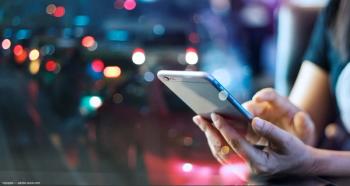 Person using phone with nighttime city backdrop Image credit: ©ipopba - adobe.stock.com