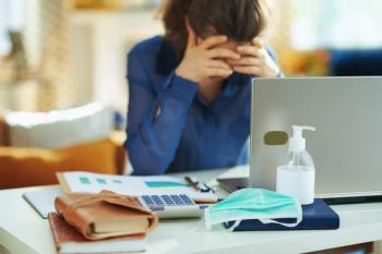 Woman holding head at desk Image credit: AdobeStock/Alliance