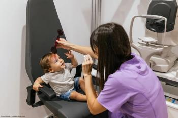 Pediatric optometrist conducting eye exam on patient Image credit: AdobeStock/JordiMora