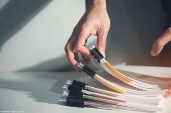 Person organizing files on table Image credit: AdobeStock/ARAMYAN