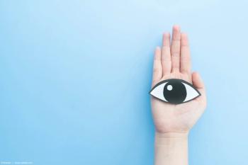 Hand holding paper cutout of eye against blue backdrop Image Credit: AdobeStock/Orawan