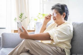 Older woman with glasses holding phone at distance Image credit: AdobeStock/KMPZZZ