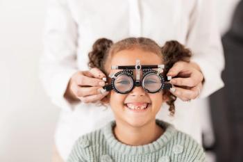 Optometrist fitting child with lens to test vision Image credit: AdobeStock/AlexisS/peopleimages.com