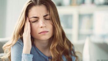 A woman holds her head in pain. Image credit: AdobeStock/sebra