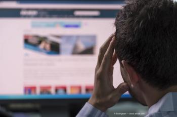 Man holds head in front of computer