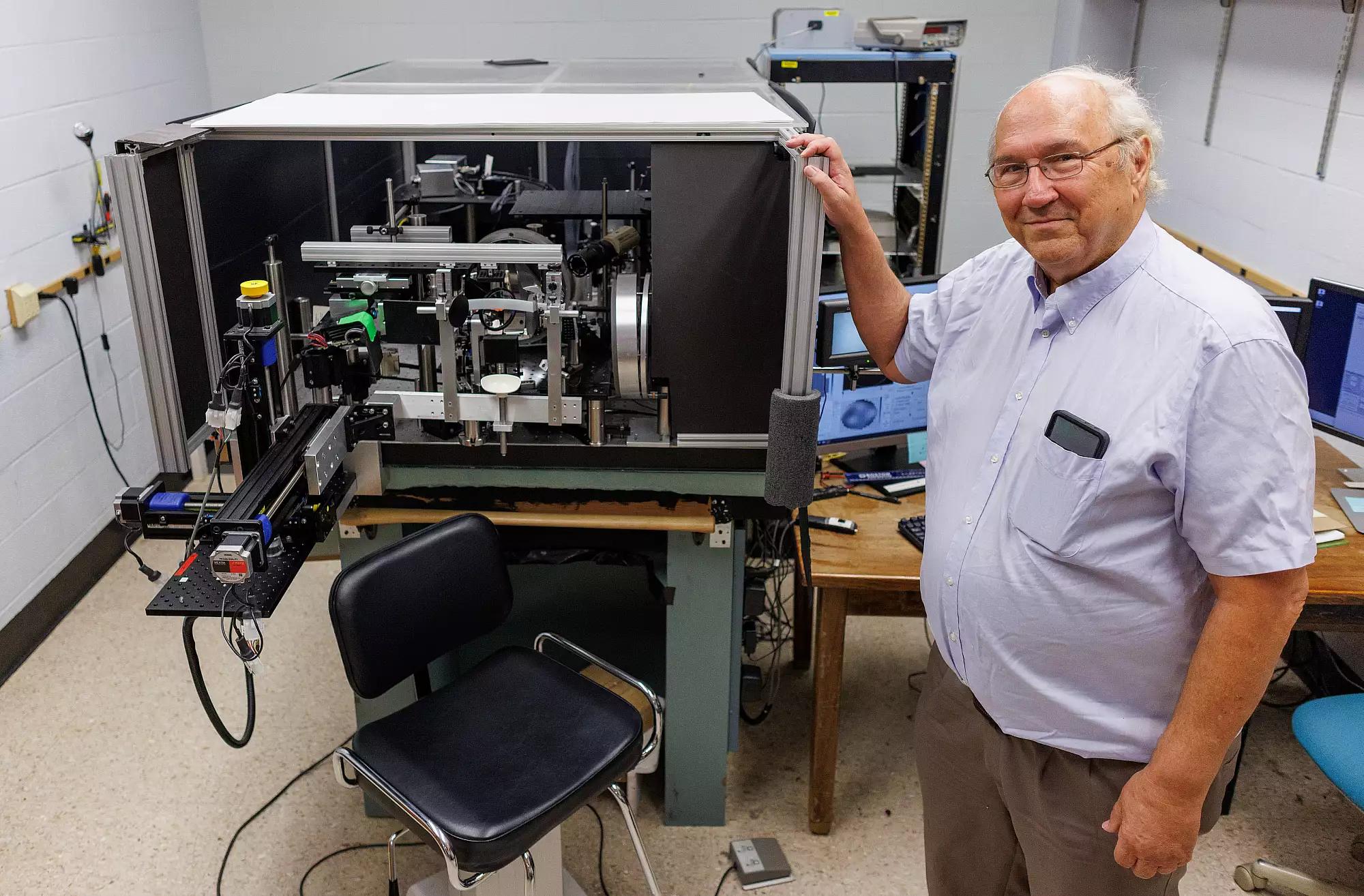 Stephen Burns standing next to ophthalmoscope Image credit: ChrisMeyer/IndianaUniversity