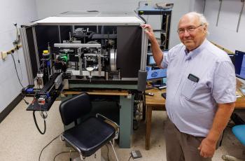 Stephen Burns standing next to ophthalmoscope Image credit: ChrisMeyer/IndianaUniversity