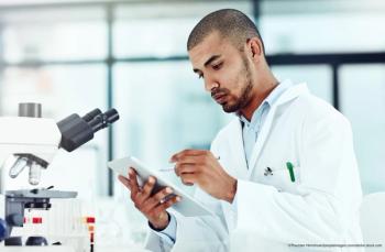 Male scientist updating tablet in lab Image Credit: ©Thurstan Hinrichsen/peopleimages.com