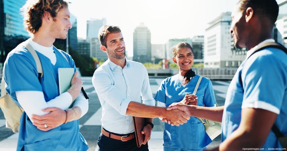 Group of doctors shaking hands Image credit: AdobeStock/peopleimages.com