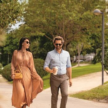 A man and woman walking outside with sunglasses on. Image credit: HOYA Vision Care