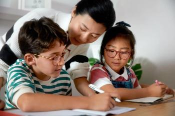 Parent helping two children with homework Image credit: SightGlass Vision