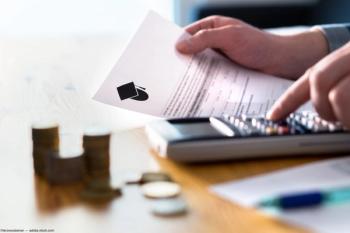 Person punching numbers in calculator with papers on desk Image credit: AdobeStock/terovesalainen