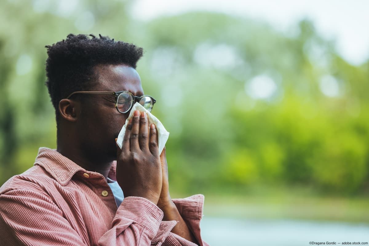 Man sitting outside sneezing into tissue Image credit: ©Dragana Gordic - adobe.stock.com