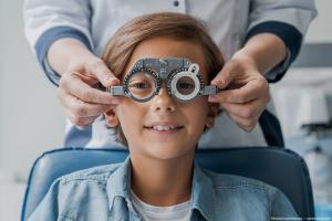 Boy sitting in pediatric office getting vision testing done by physician Image credit: ©InsideCreativeHouse - adobe.stock.com