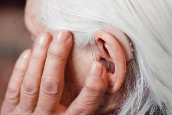 Older woman touching hearing aid Image credit: AdobeStock/dmytro_khlystun