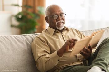 man reading in dim lighting conditions may benefit from phentolamine ophthalmic solution - Image credit: Adobe Stock / Prostock-studio