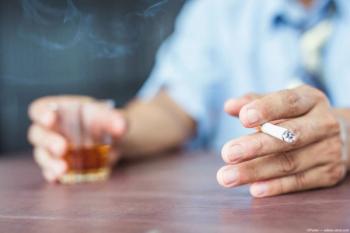 Man holding cigarette and whiskey glass at table Image credit: AdobeStock/Parkin