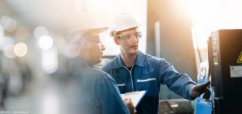 Factory workers inspecting machinery Image credit: Adobestock/Mestudio