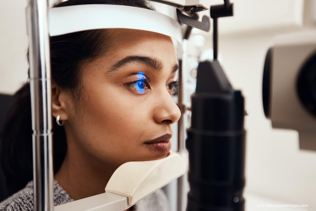 Keep as still as possible. Shot of a young woman getting her eyes examined with a slit lamp. (Adobe Stock / N Felix/peopleimages.com)