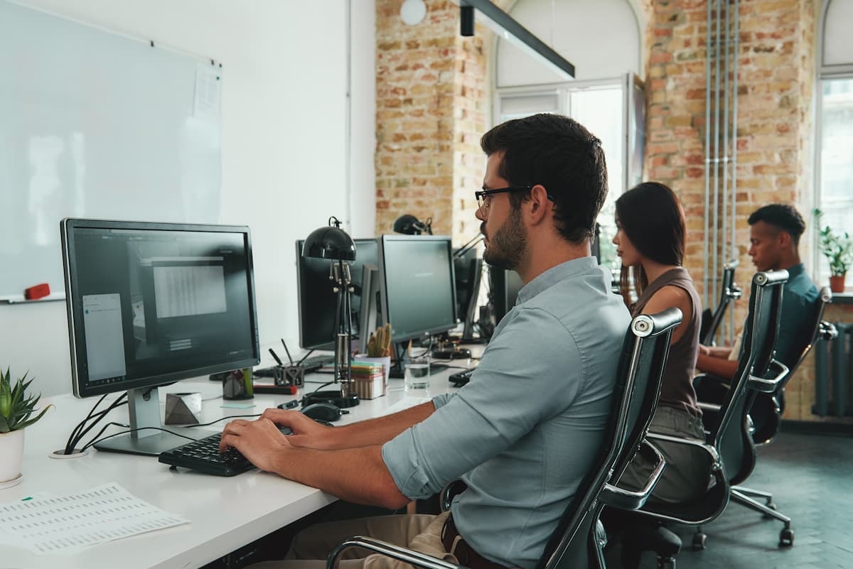 Employees working at desks Image credit: AdobeStock/FriendsStock