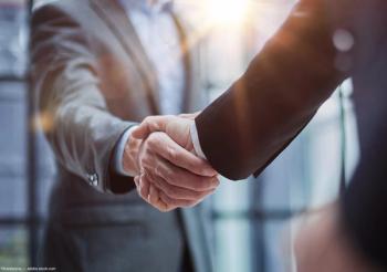 Two businessmen shake hands Image credit: AdobeStock/Katsiaryna