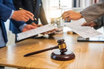 Businessmen discussing legal documents at table. Image credit: AdobeStock/M+Isolation+Photo