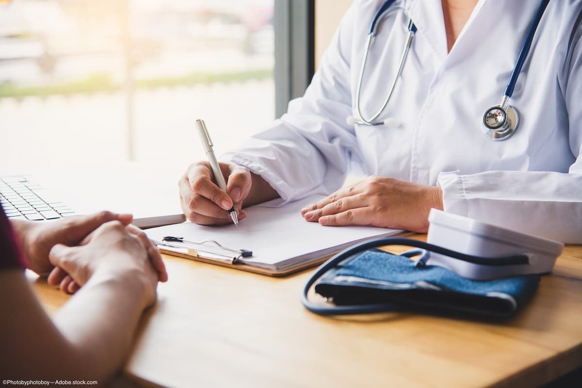 Doctor writing in notepad with patient 