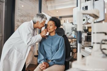 Doctor, vision or black woman in eye exam consultation or assessment for eyesight at optometrist office. Mature or senior optician helping a customer testing or checking iris or retina visual health (Adobe Stock / Coetzee/peopleimages.com)